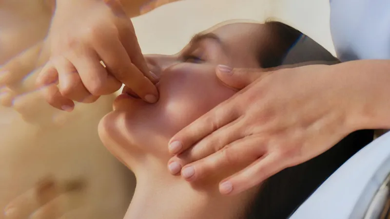 Natura Bissé facial treatment: hands massage the face of a woman lying with closed eyes