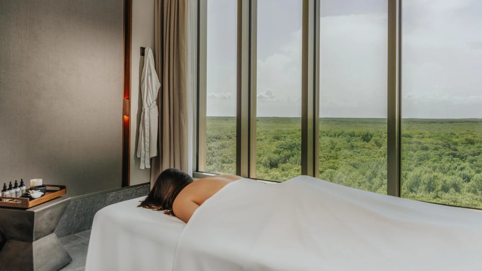 Treatment room at SHA Wellness Clinic in Mexico, a guest on the massage table and a window onto green landscape