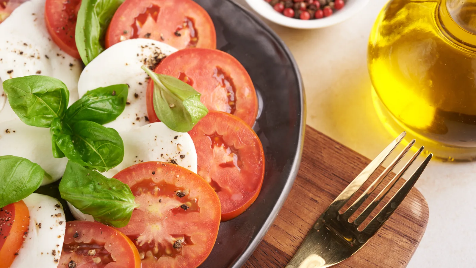 Tomatoes, mozzarella, basil and olive oil on a wooden board