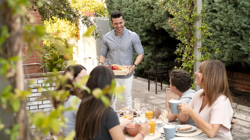 Family of several generations sharing lunch at a long table outdoors in a garden