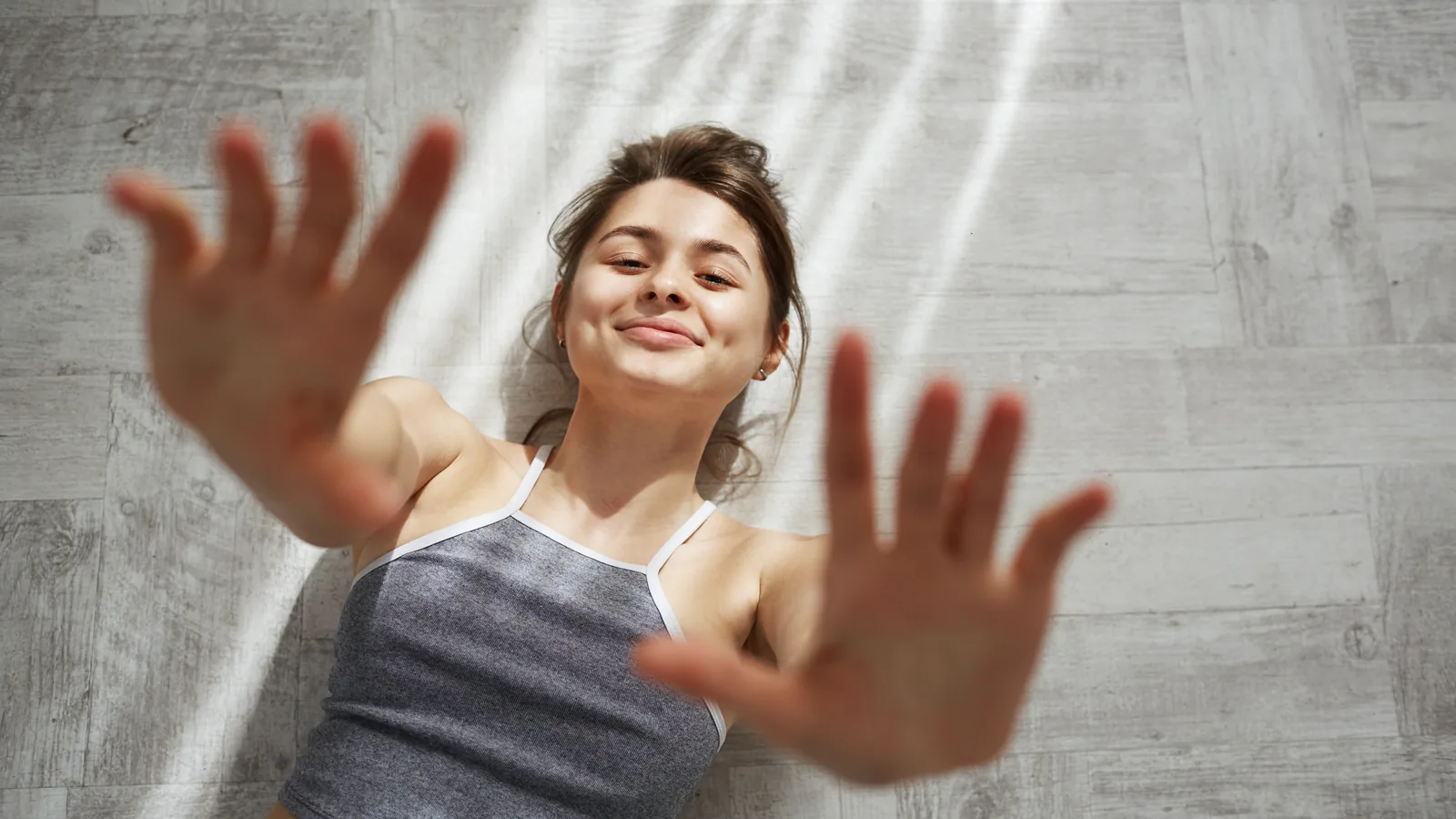 Woman reaching into the morning sunlight falling through a window